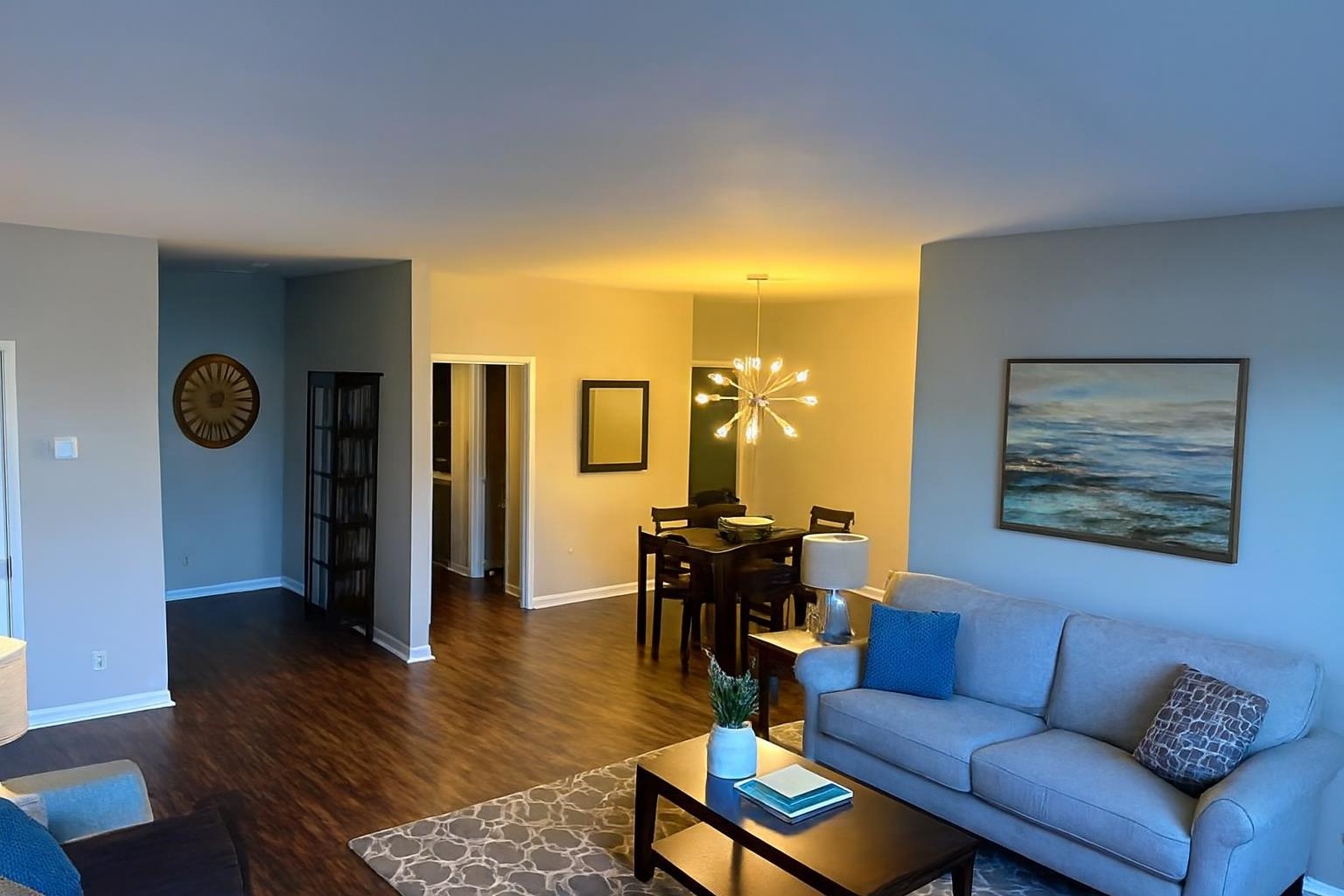 a living room with furniture a dining table and wooden floor