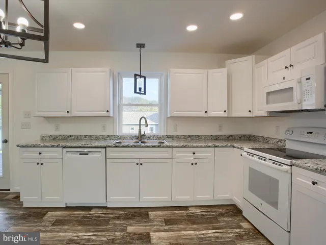 a kitchen with granite countertop white cabinets white stainless steel appliances with a sink and dishwasher