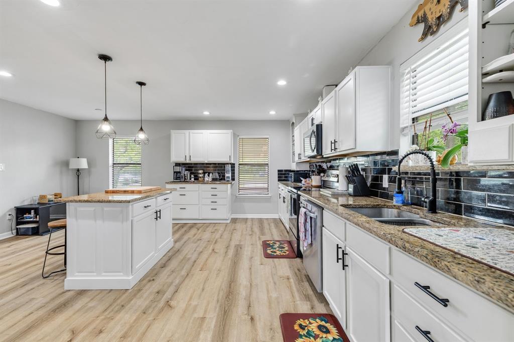 191 Klutts Road McLendon-Chisholm, TX 75032 - Photo 7 of 40 a kitchen with stainless steel appliances granite countertop a sink dishwasher a stove a microwave oven and a dining table with wooden floor