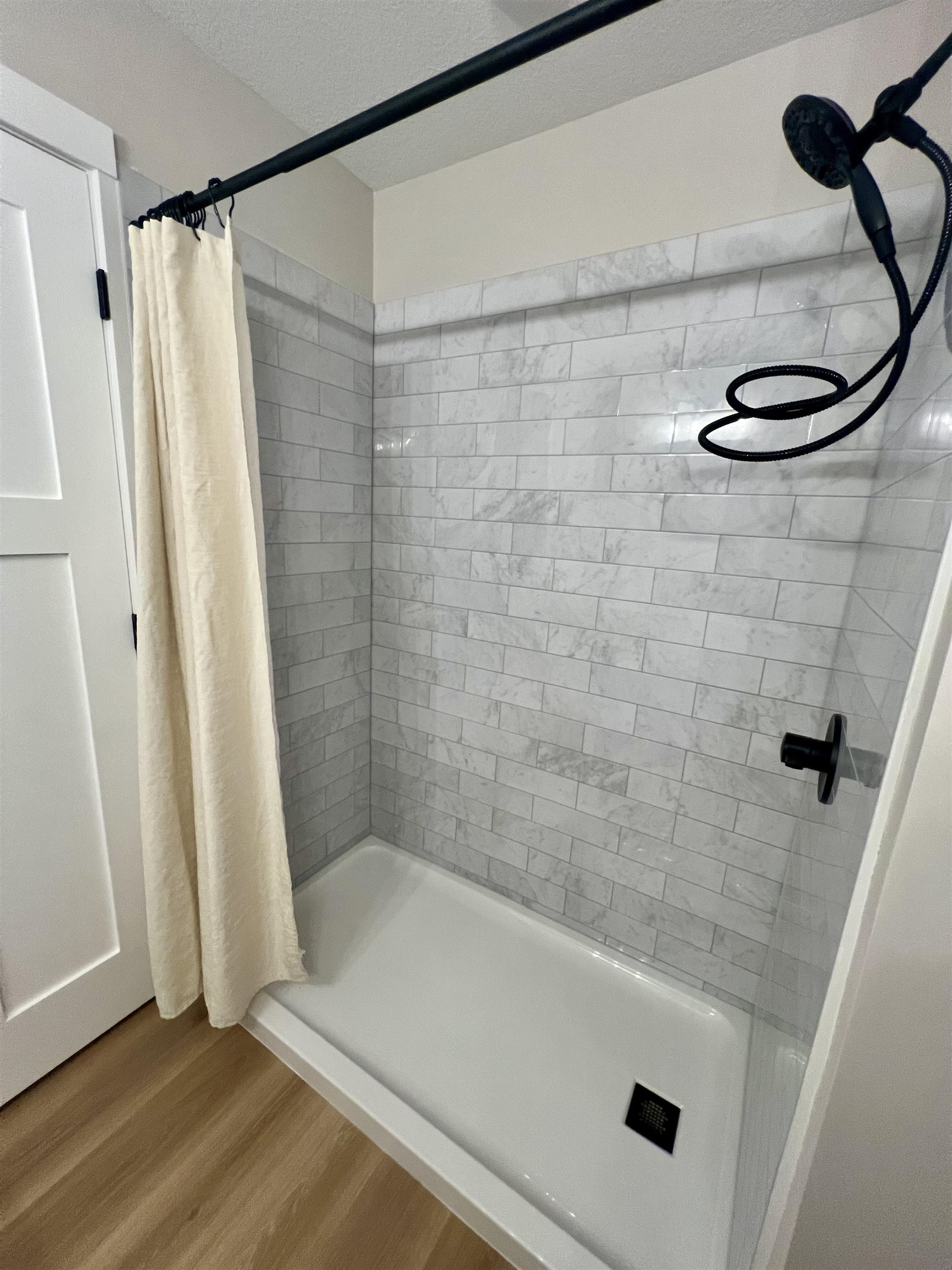 1006 26th Street, Unit B Cloquet, MN 55720 - Photo 17 of 27 Full bathroom featuring a stall shower, wood finished floors, and a textured ceiling