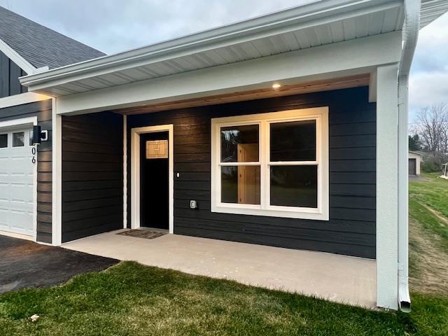 1006 26th Street, Unit B Cloquet, MN 55720 - Photo 3 of 27 Entrance to property with covered porch, a garage, a shingled roof, and a yard