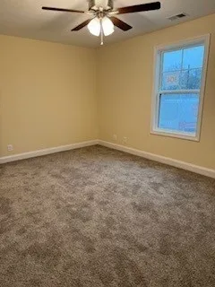 an empty room with a chandelier fan and windows