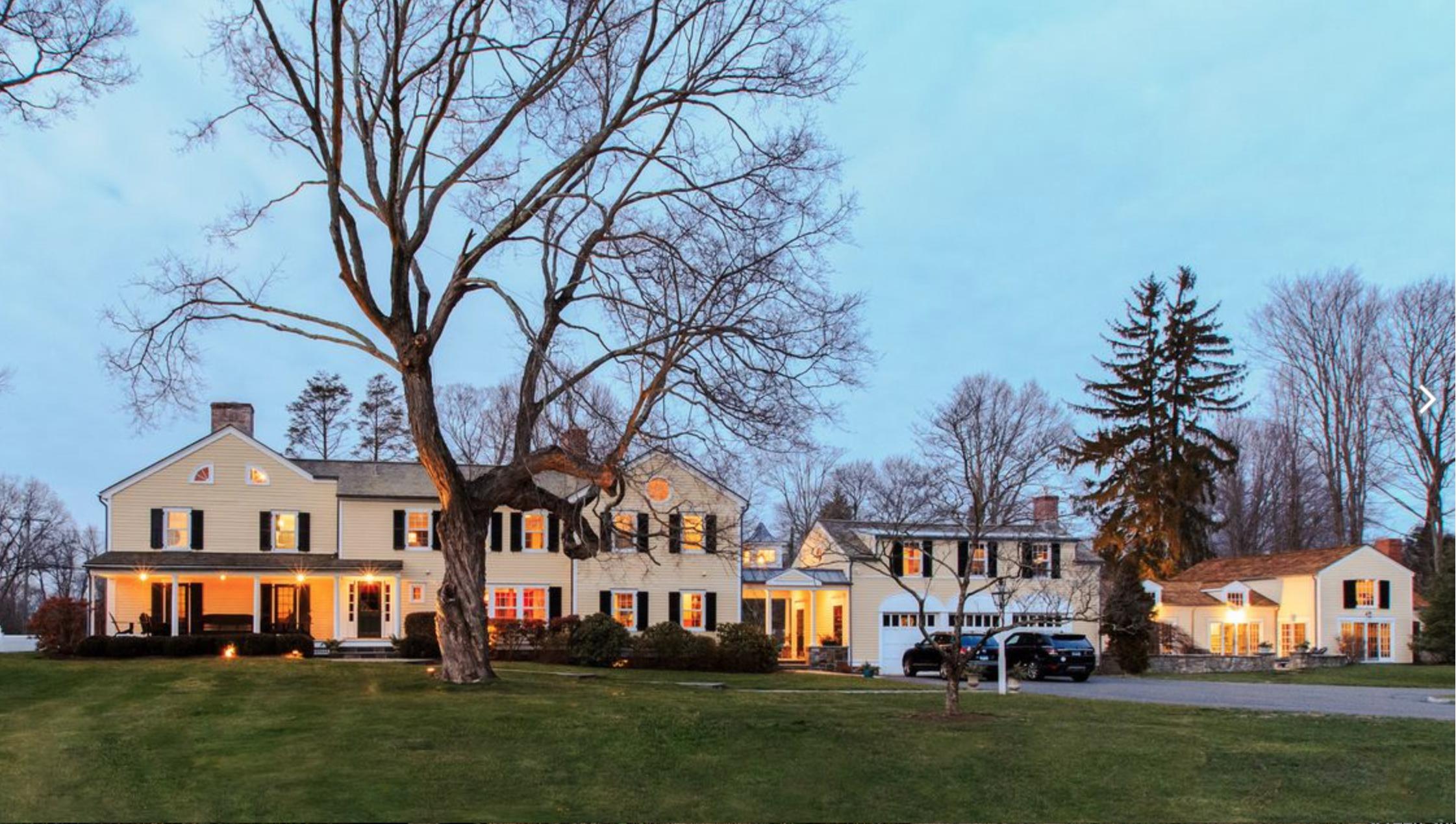 991 Ponus Ridge Road New Canaan, CT 06840 - Photo 2 of 12 a view of a white house next to a yard with big trees and wooden fence