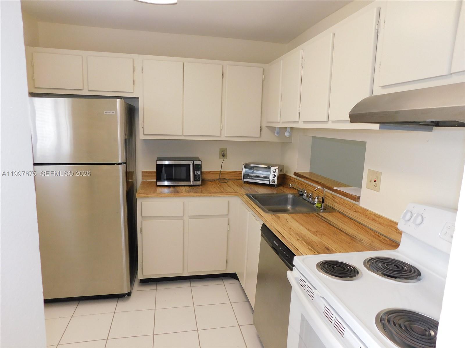 8005 Southwest 107th Avenue, Unit 309 Miami, FL 33173 - Photo 2 of 18 a kitchen with a refrigerator sink and cabinets