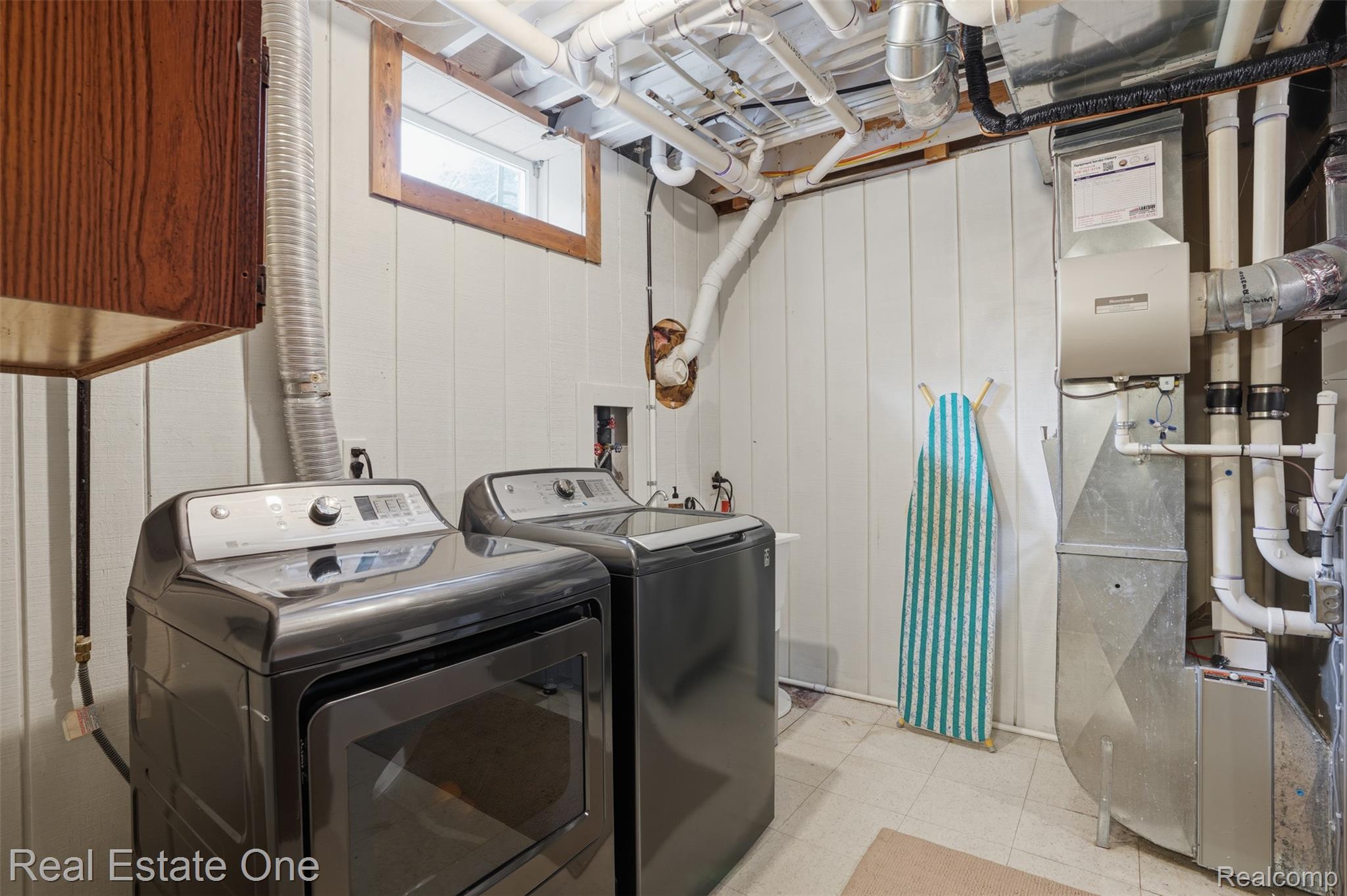 1765 Rowe Road Milford, MI 48380 - Photo 38 of 61 Dedicated laundry area featuring paneled walls, a single-pane window with wood trim, and visible overhead utility lines