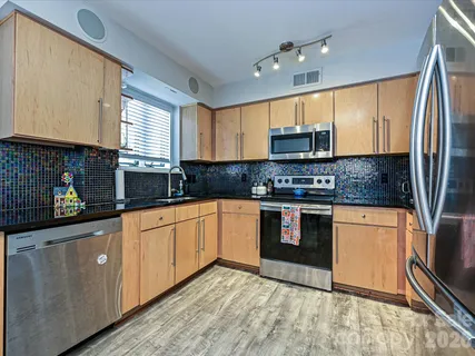 a kitchen with stainless steel appliances granite countertop a sink a stove a refrigerator cabinets and a window