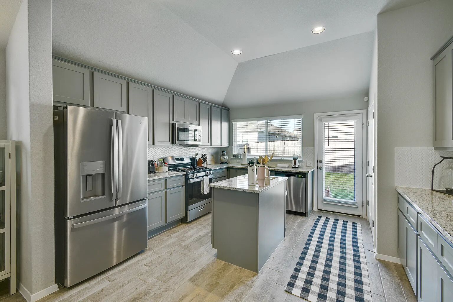 121 Crescent Street Georgetown, TX 78626 - Photo 8 of 27 Kitchen with gray cabinetry, stainless steel appliances, backsplash, light wood finished floors, and lofted ceiling