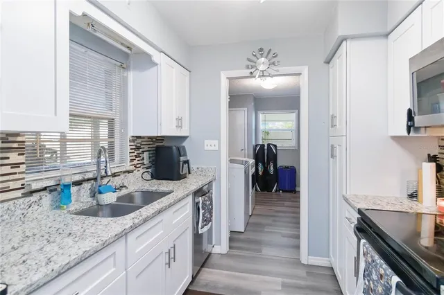 a kitchen with granite countertop a sink dishwasher stove and cabinets