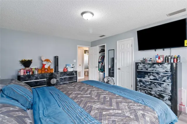 a bedroom with bed and a flat tv screen on wall