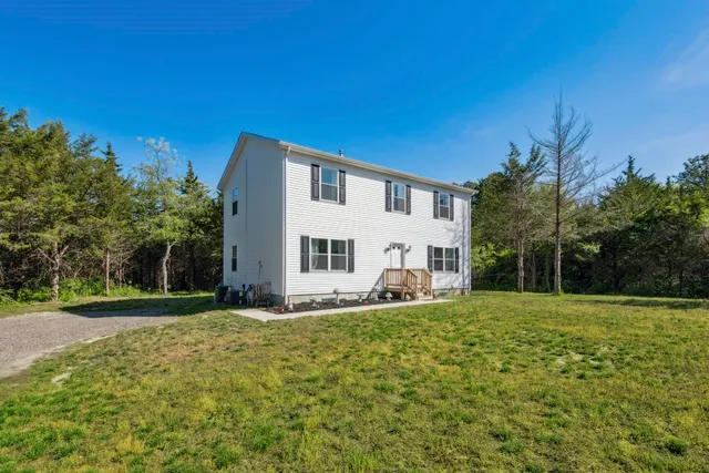 a white house with a big yard and large trees