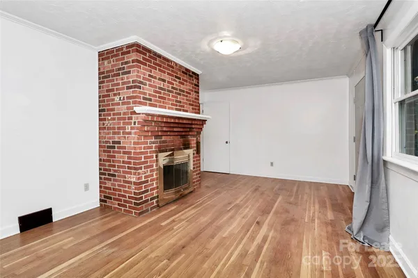 a view of empty room with wooden floor and fireplace