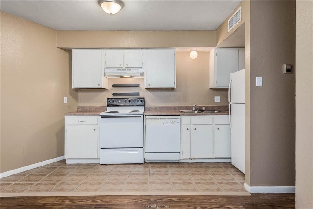 3900 Old College Road, Unit 10 Bryan, TX 77801 - Photo 5 of 12 a kitchen with cabinets appliances and a wooden floor