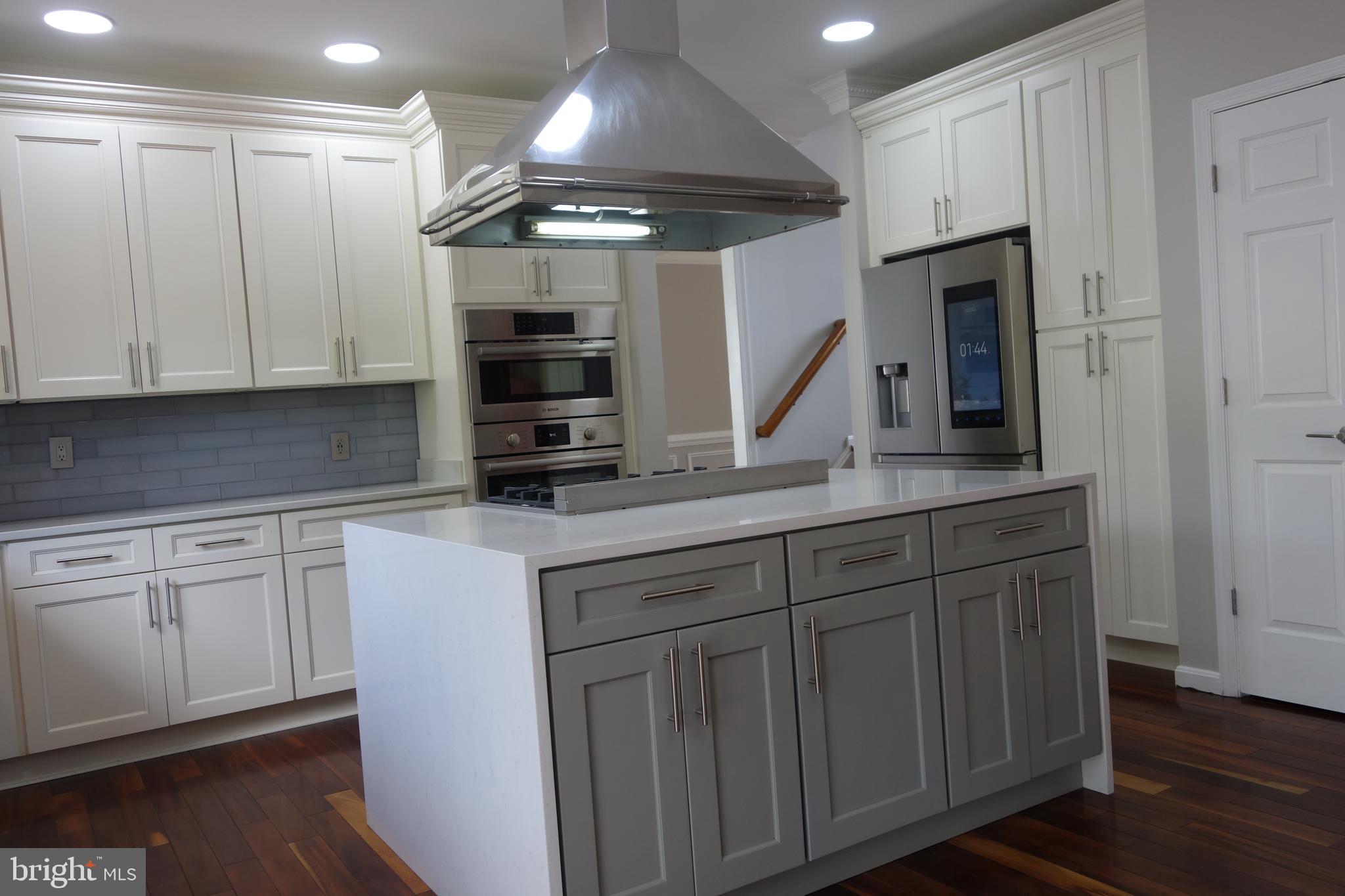 8196 Tenbrook Drive Gainesville, VA 20155 - Photo 18 of 51 a kitchen with stainless steel appliances granite countertop a sink a stove and a microwave with wooden floor