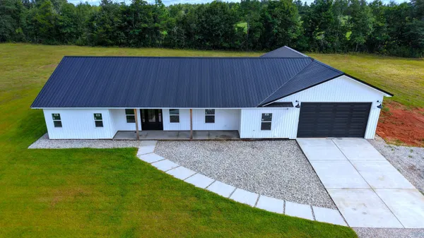 a front view of house with yard and trees in the background