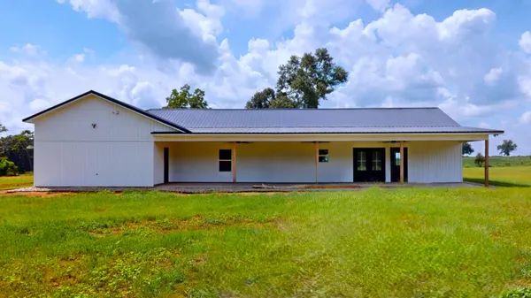 a front view of house with yard and trees in the background