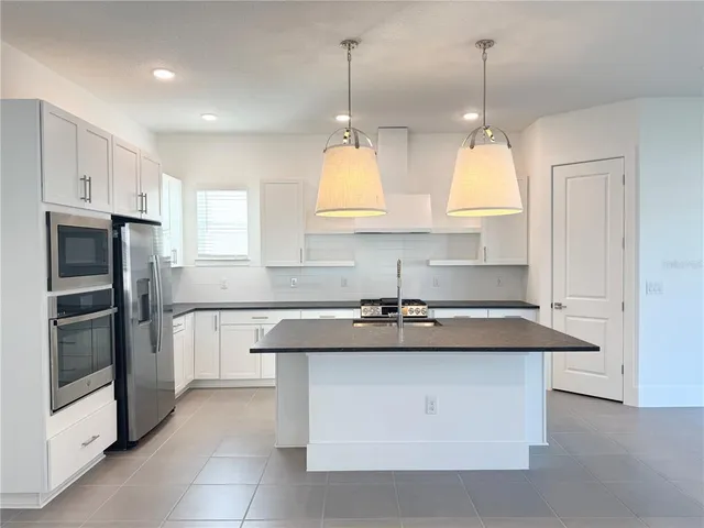 a kitchen with stainless steel appliances granite countertop a sink a stove and a refrigerator