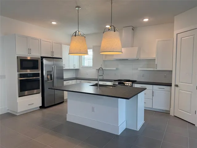 a kitchen with stainless steel appliances granite countertop a sink a stove and a refrigerator