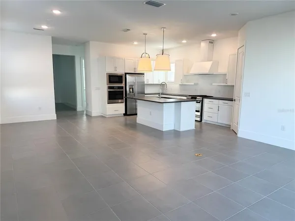 a large kitchen with a large counter top space a sink stainless steel appliances and cabinets