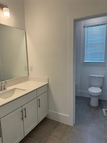 a bathroom with a granite countertop toilet sink and mirror