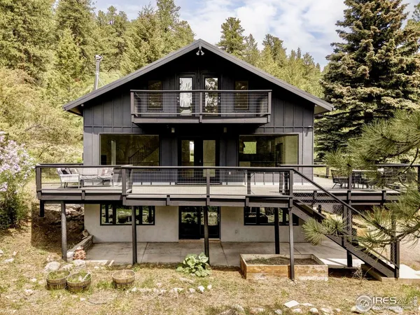 a view of a house with pool chairs and wooden fence
