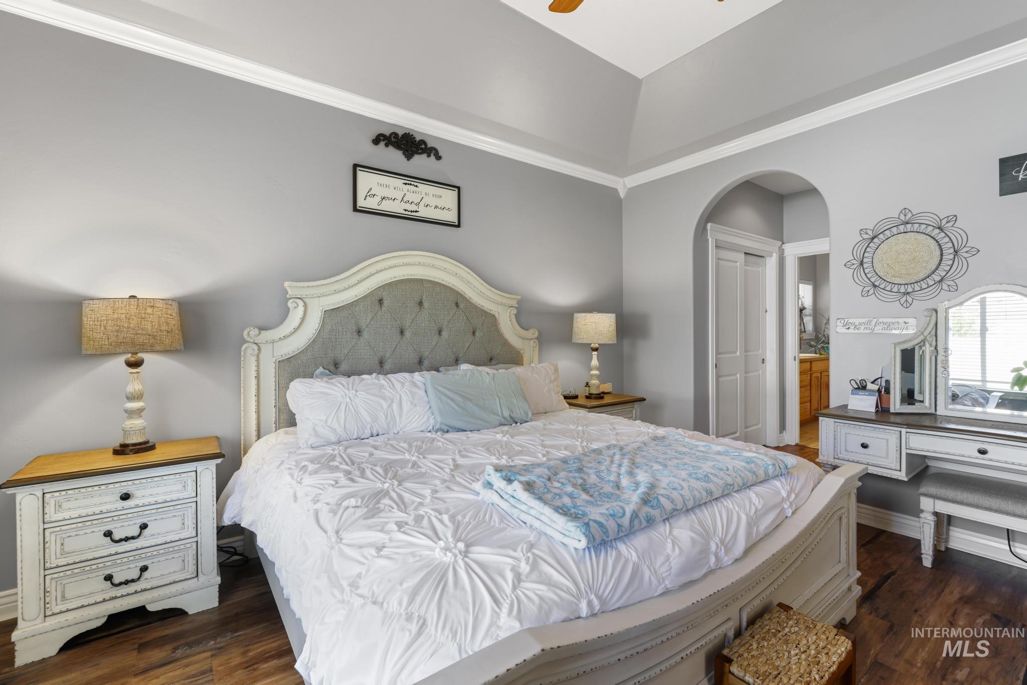 467 Wildrose Loop Twin Falls, ID 83301 - Photo 23 of 46 Vaulted ceiling bedroom featuring wood-finish flooring, an arched doorway, crown molding, and bi-fold closet doors