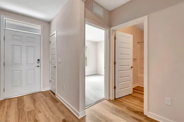 an empty room with wooden floor closet and windows