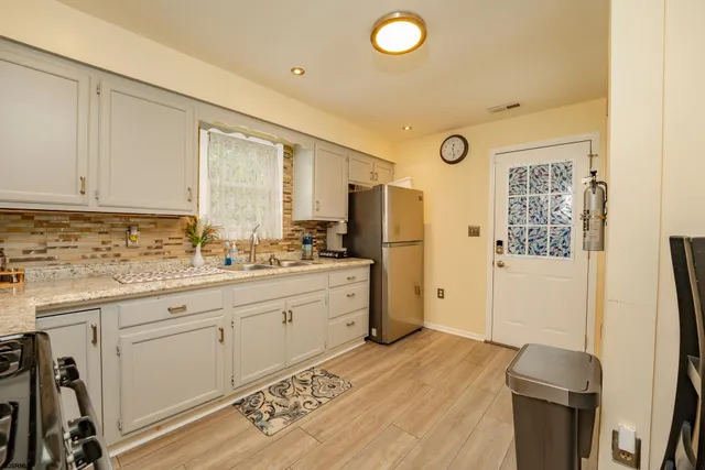 a kitchen with stainless steel appliances a refrigerator sink and white cabinets