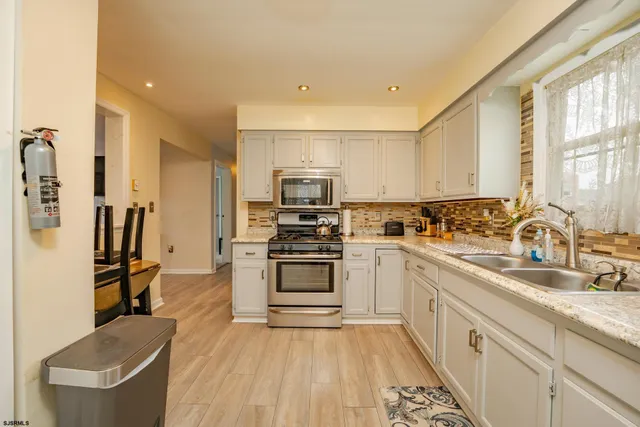 a large kitchen with stainless steel appliances granite countertop a stove a sink dishwasher and a refrigerator