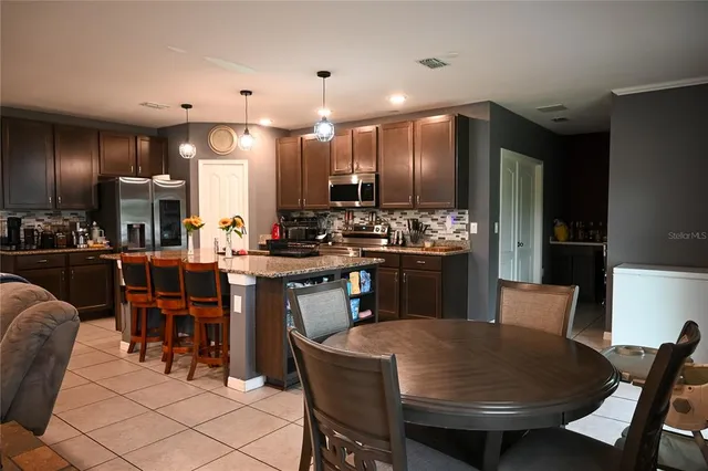a kitchen with stainless steel appliances kitchen island granite countertop a refrigerator and a stove