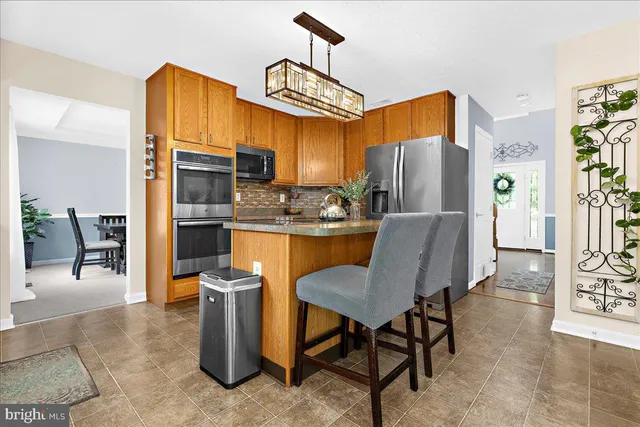a kitchen with stainless steel appliances granite countertop a refrigerator a stove top oven a sink dishwasher and white cabinets with wooden floor
