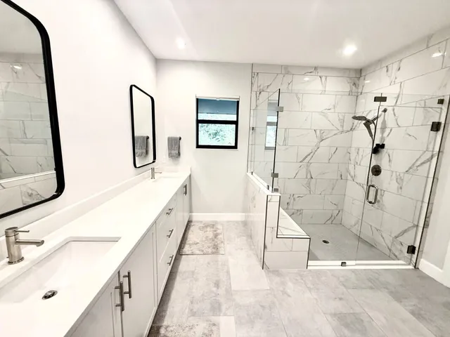 a spacious bathroom with a double vanity sink a mirror and a shower