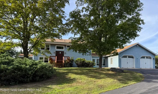 a front view of a house with a garden and trees