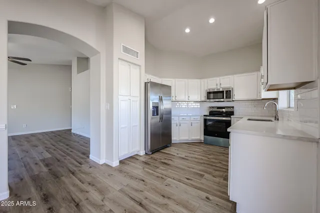 a kitchen with cabinets stainless steel appliances and a window