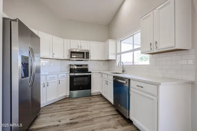 a kitchen with stainless steel appliances cabinets and wooden floor