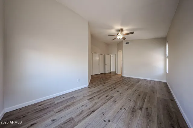 a view of a room with wooden floor and a ceiling fan