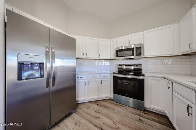 a kitchen with granite countertop a refrigerator oven a sink dishwasher and wooden cabinets