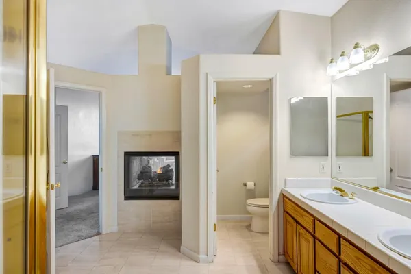 a bathroom with a double vanity sink and mirror with toilet