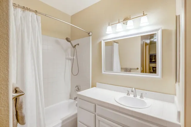 a bathroom with a sink vanity granite tub shower and a mirror