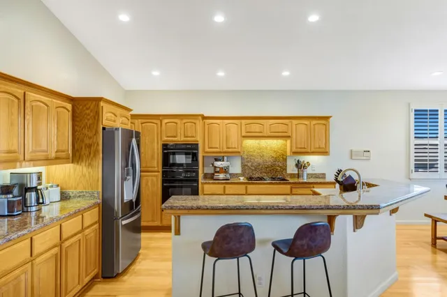 a kitchen with stainless steel appliances granite countertop a sink and a refrigerator