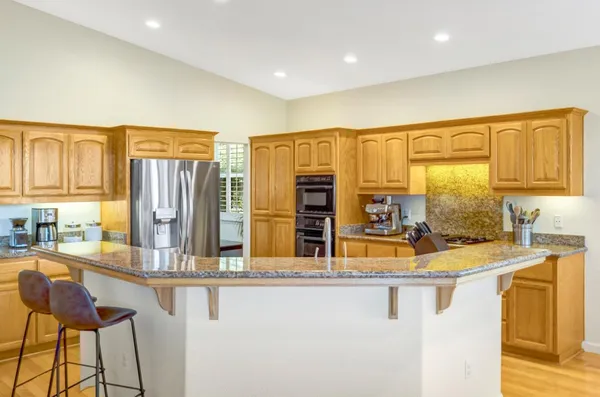 a kitchen with stainless steel appliances granite countertop a sink and a refrigerator
