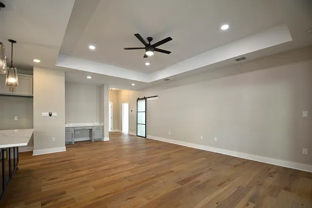 an empty room with wooden floor and a ceiling fan