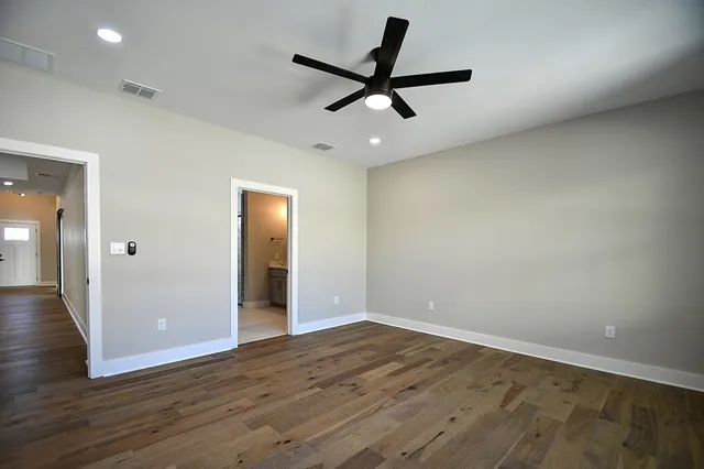 an empty room with wooden floor and a ceiling fan