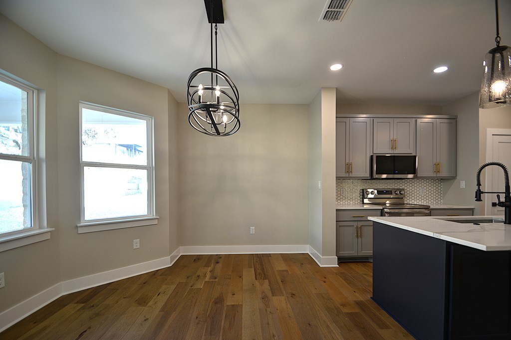 1806 Chateau Kerrville, TX 78028 - Photo 6 of 44 a kitchen with stainless steel appliances granite countertop a sink a stove a refrigerator cabinets and a dining table with wooden floor