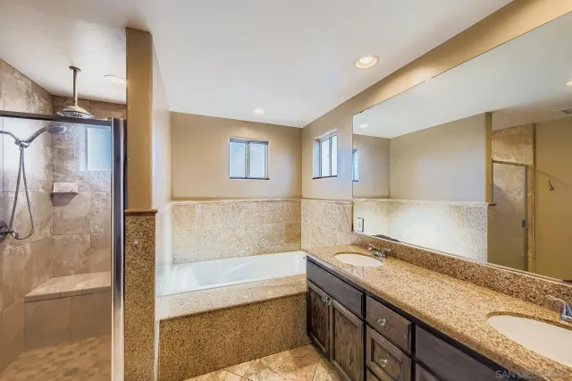 a bathroom with a granite countertop sink a mirror and a bathtub