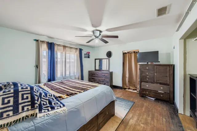 a bedroom with a bed a dresser and flat screen tv