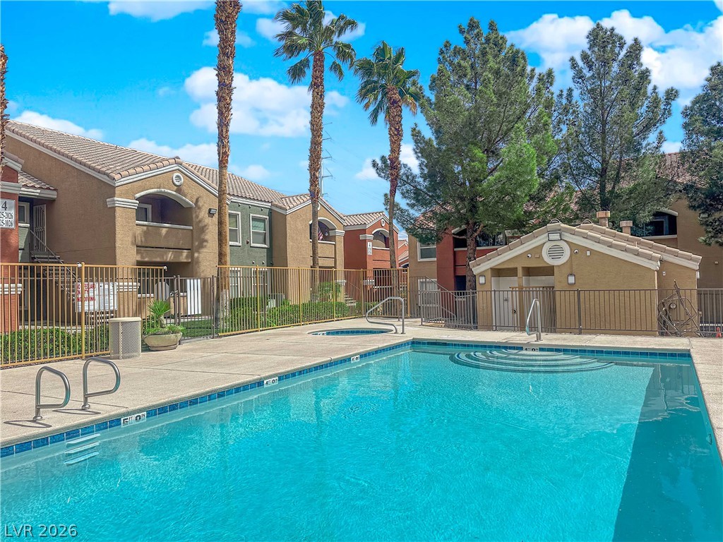 8101 West Flamingo Road, Unit 2030 Las Vegas, NV 89147 - Photo 9 of 27 An inviting swimming pool and spa nestled among residential buildings under a bright sky, perfect for recreation.