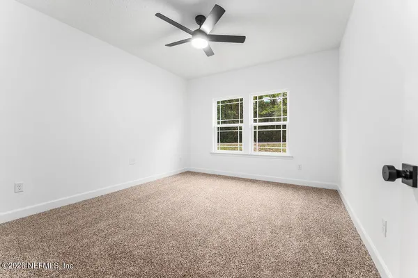 an empty room with a window and a ceiling fan