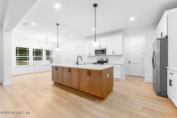 a large kitchen with stainless steel appliances kitchen island granite countertop a stove a sink a refrigerator a center island a refrigerator and a wooden floor