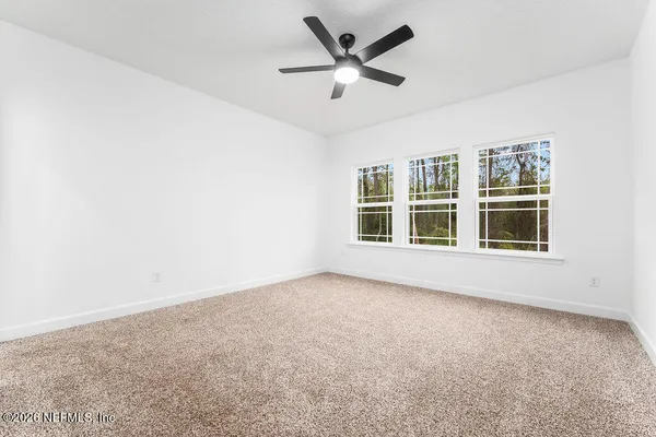 an empty room with windows and ceiling fan