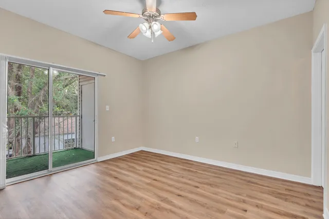 a view of empty room with wooden floor and fan